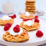 Fluffy Homemade Waffles topped with whipped cream and fresh raspberries