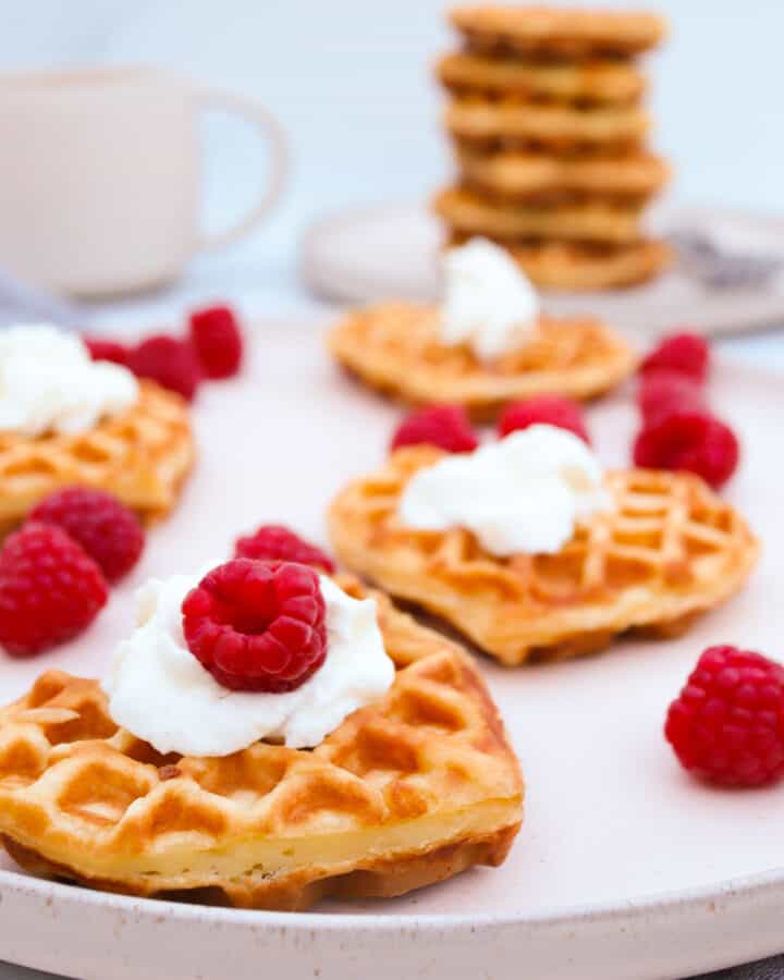 Fluffy Homemade Waffles topped with whipped cream and fresh raspberries