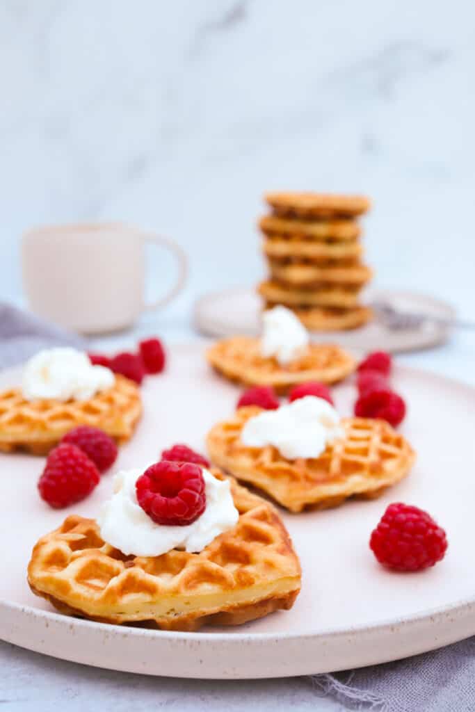 Homemade fluffy waffles served with whipped cream, fresh raspberries, and coffee