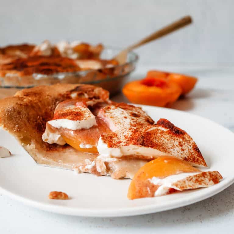 A slice of Sour Cream Peach Pie with fresh peaches