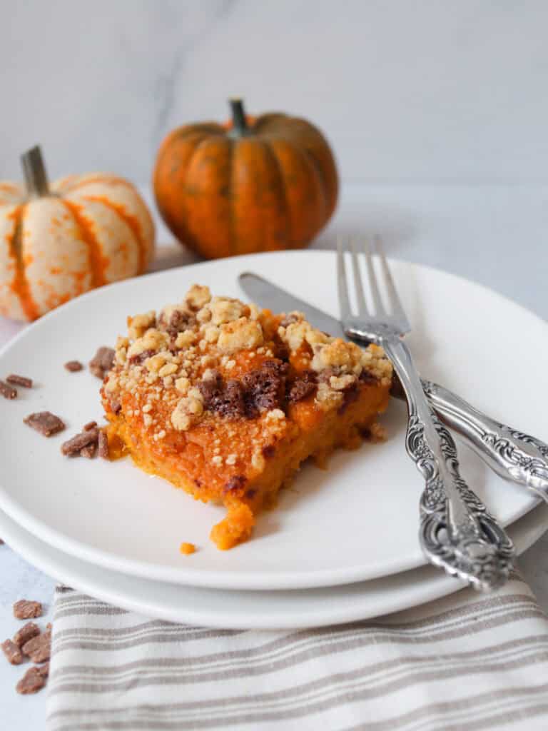 Sweet potato soufflé with fork and knife and pumpkins in the background