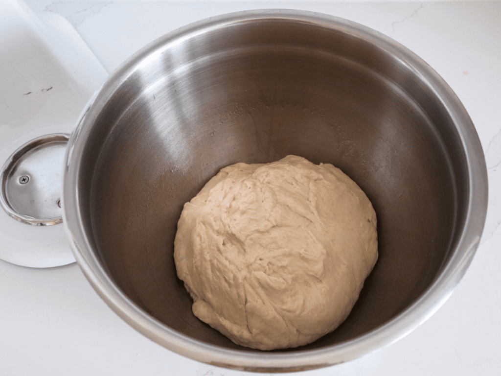 Picture of the dough being formed into a round ball in a stainless steel bowl