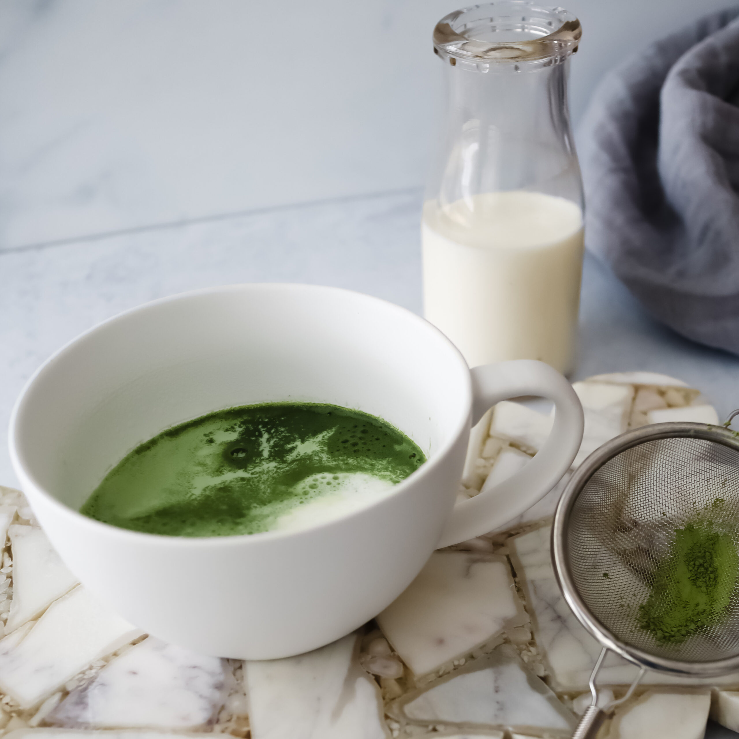 Rishi Tea Barista Matcha powder, almond milk, and honey arranged on a marble surface for an easy matcha latte recipe