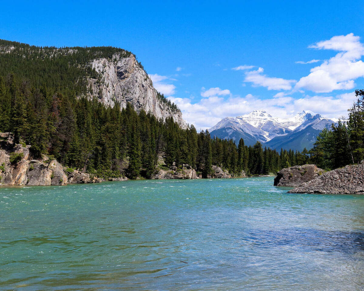 Bow Falls and the Bow River in Banff with snow capped peaks in the distance