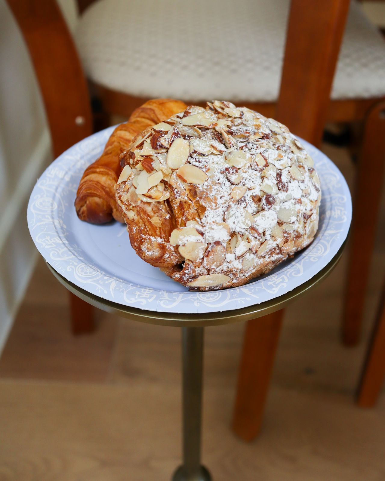 An almond croissant and plain croissant from Village Baking Co. on a plate