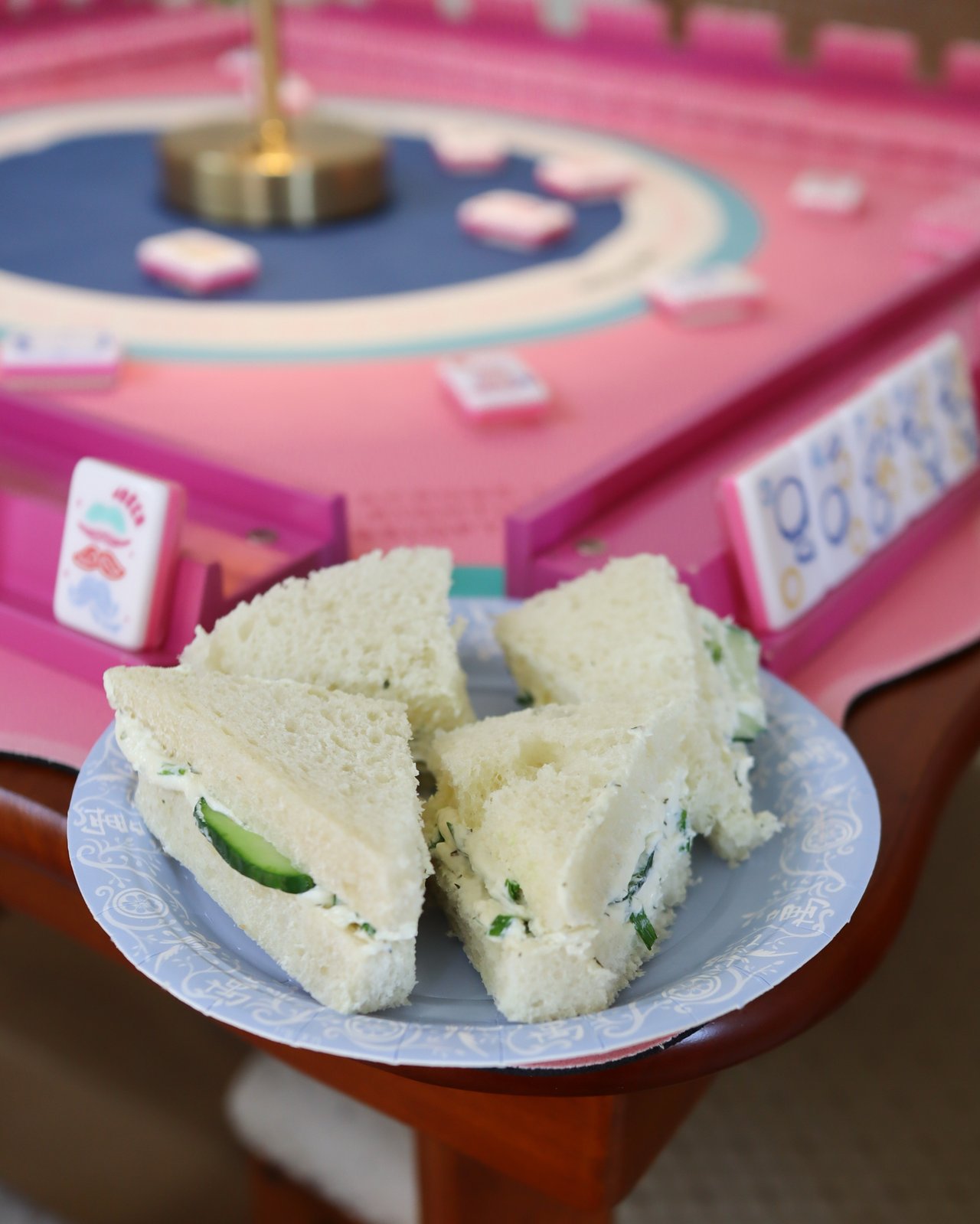 Cucumber tea sandwiches on a plate beside pink mahjong tiles